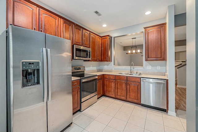 kitchen featuring light tile patterned flooring, stainless steel appliances, sink, and hanging light fixtures