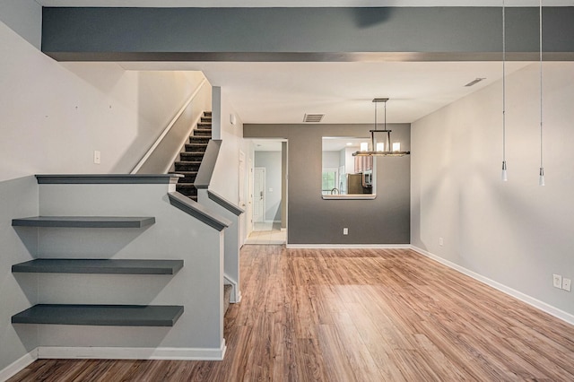 stairs with hardwood / wood-style floors and a notable chandelier