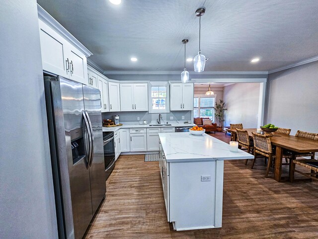 kitchen featuring white cabinets, appliances with stainless steel finishes, a center island, decorative light fixtures, and dark hardwood / wood-style floors