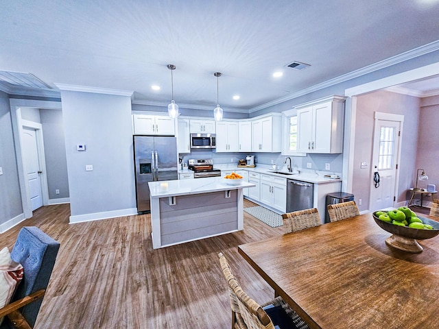 kitchen featuring decorative light fixtures, a kitchen island, sink, stainless steel appliances, and white cabinets