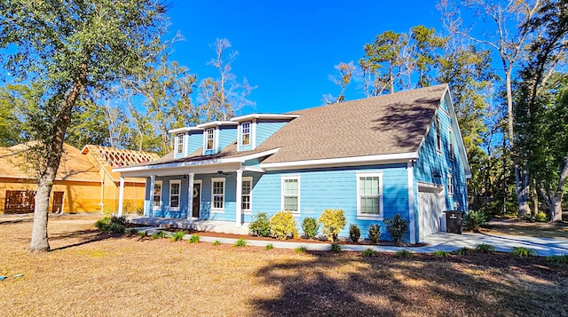 view of front of house with a front yard, covered porch, and a garage