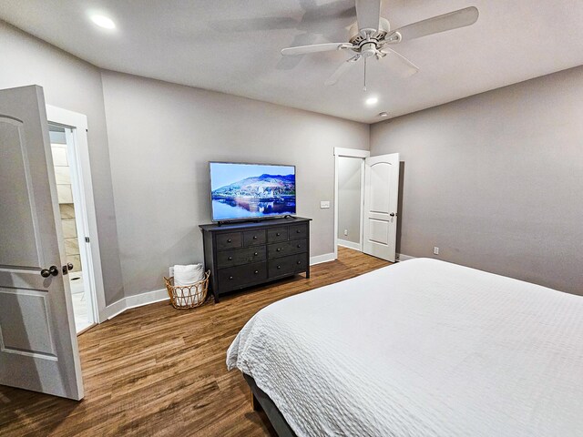 bedroom with ceiling fan, dark wood-type flooring, and connected bathroom