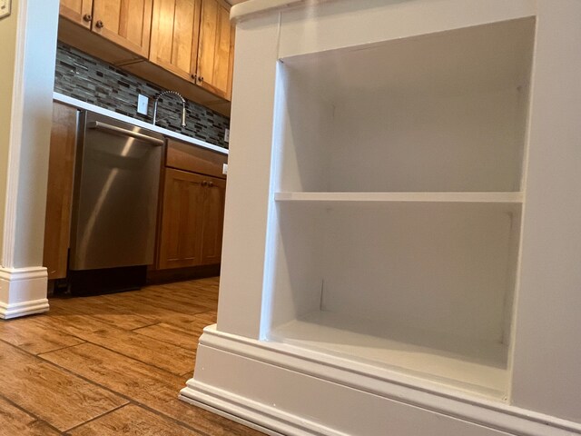 kitchen featuring stainless steel dishwasher, backsplash, and light wood-type flooring