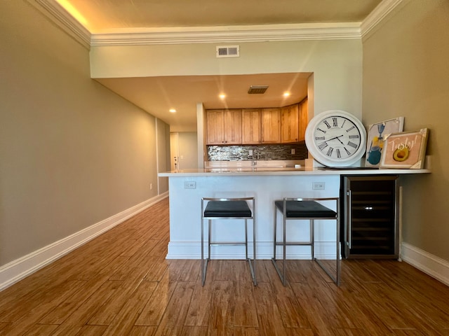 kitchen with wine cooler, kitchen peninsula, dark wood-type flooring, tasteful backsplash, and a breakfast bar