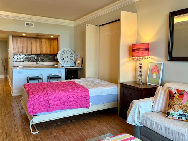 bedroom with sink, dark hardwood / wood-style flooring, and ornamental molding