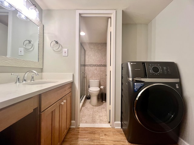 bathroom with an enclosed shower, toilet, wood-type flooring, washer / clothes dryer, and vanity