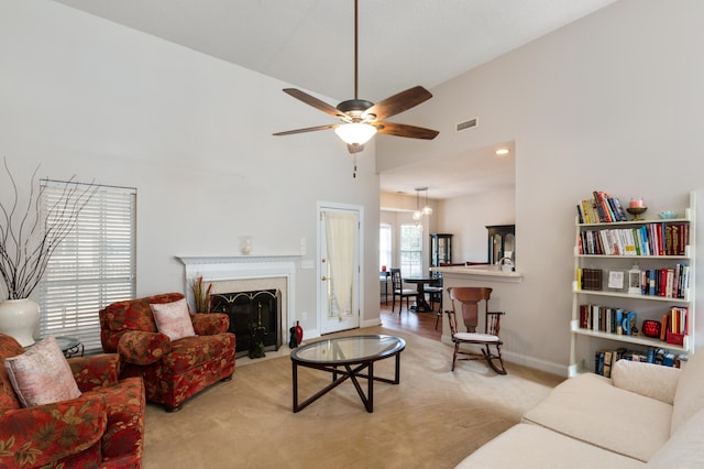 living room featuring light carpet, a towering ceiling, and ceiling fan