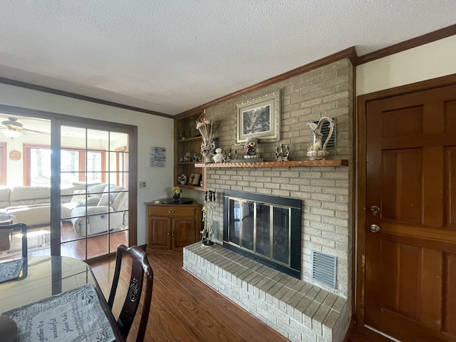 living room featuring dark wood-style floors, a textured ceiling, a brick fireplace, and crown molding