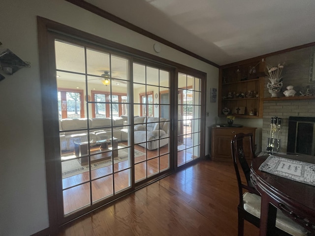 interior space featuring ceiling fan, ornamental molding, a fireplace, and dark wood finished floors