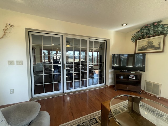 living area with a textured ceiling, wood finished floors, and visible vents