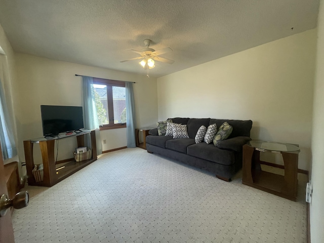 carpeted living room with ceiling fan, a textured ceiling, and baseboards