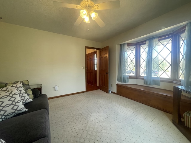 living room with a textured ceiling, ceiling fan, light colored carpet, and baseboards