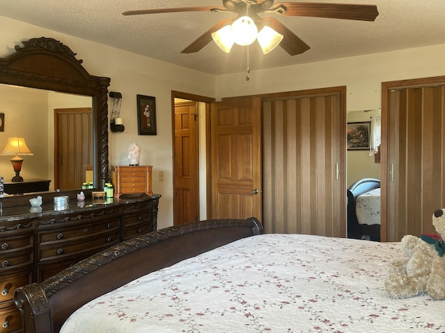 bedroom featuring multiple closets, ceiling fan, and a textured ceiling