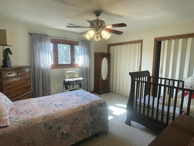 carpeted bedroom featuring ceiling fan and a textured ceiling