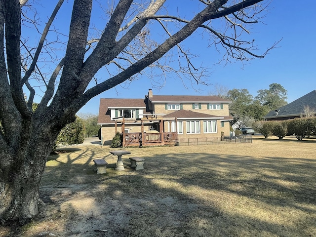 rear view of house with a wooden deck, a chimney, and a yard