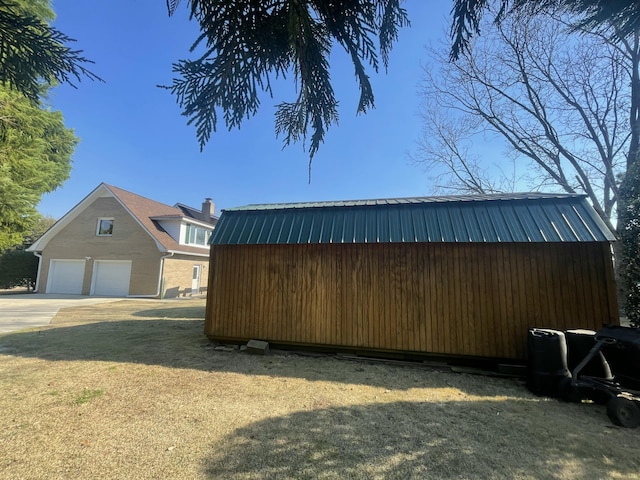 view of side of home featuring a garage, metal roof, a lawn, and an outbuilding