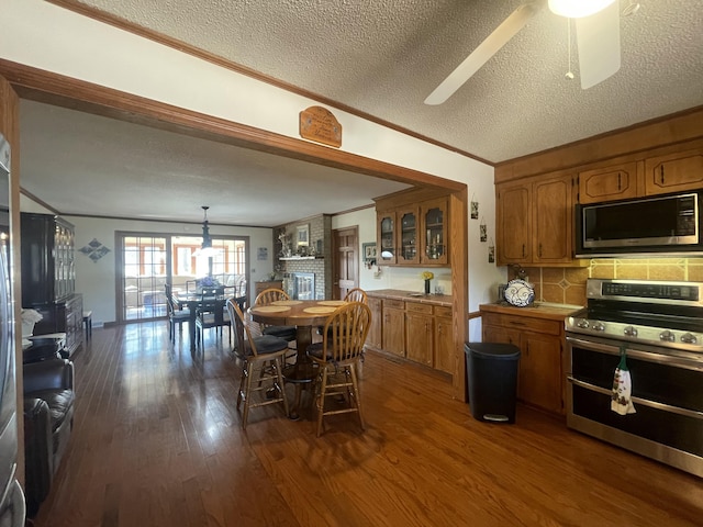 kitchen with tasteful backsplash, brown cabinetry, range with two ovens, dark wood-style flooring, and crown molding