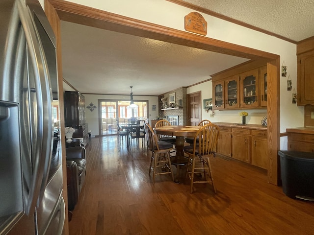 dining space with dark wood-style floors, crown molding, and a textured ceiling