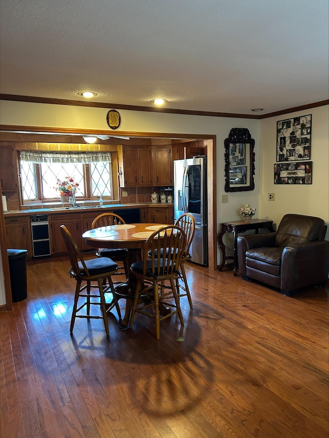 dining space featuring dark wood finished floors, crown molding, and a textured ceiling