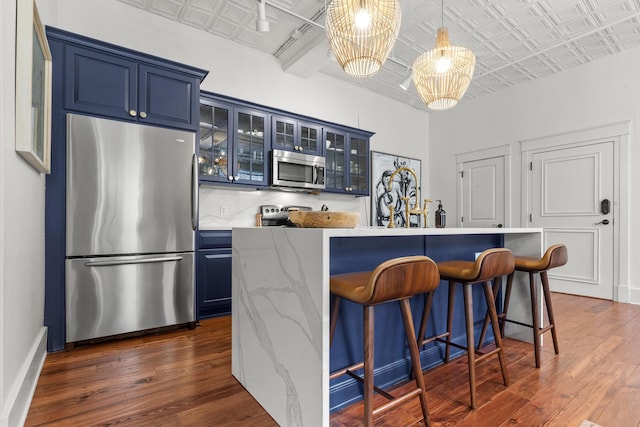 4 Beaufain St Unit 207, Charleston, SC 29401 - kitchen with stainless steel appliances, blue cabinets, an ornate ceiling, dark wood-style flooring, and a kitchen bar