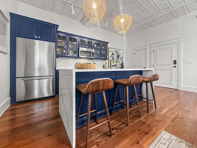 4 Beaufain St Unit 207, Charleston, SC 29401 - kitchen with stainless steel appliances, an ornate ceiling, blue cabinets, dark wood-style floors, and a breakfast bar area