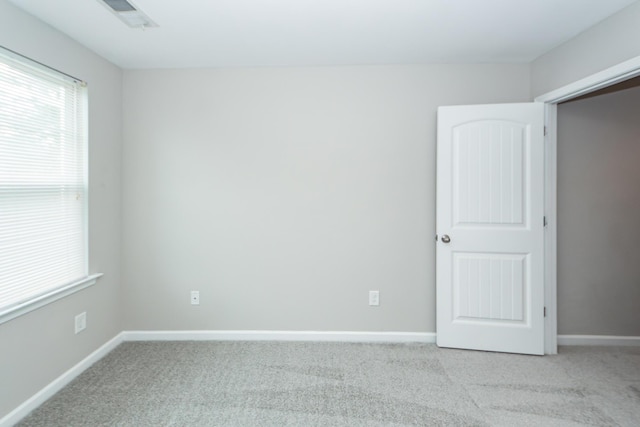 spare room with carpet flooring, baseboards, and visible vents