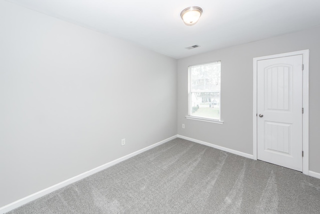 carpeted spare room featuring visible vents and baseboards