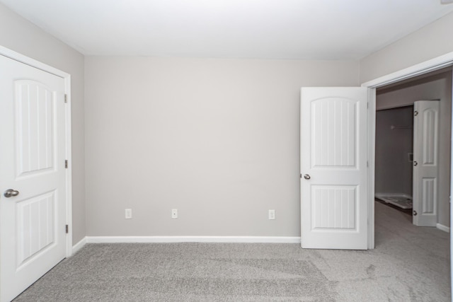 unfurnished bedroom featuring baseboards and light carpet