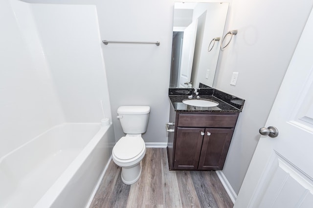 full bath with toilet, shower / washtub combination, wood finished floors, baseboards, and vanity