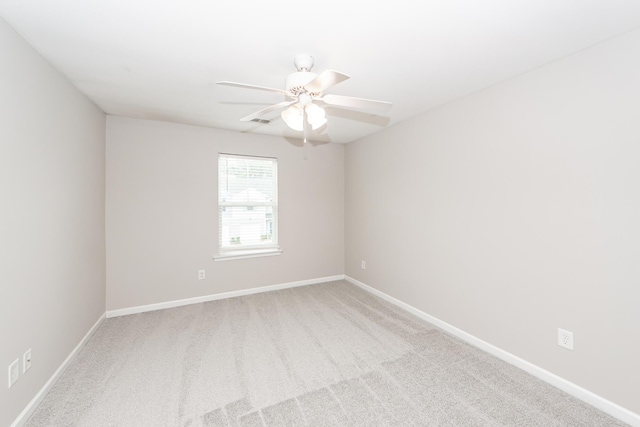 carpeted empty room with visible vents, a ceiling fan, and baseboards