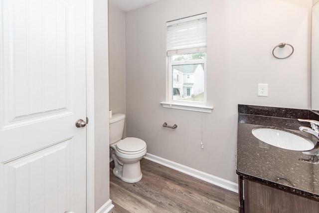 bathroom featuring baseboards, toilet, wood finished floors, and vanity