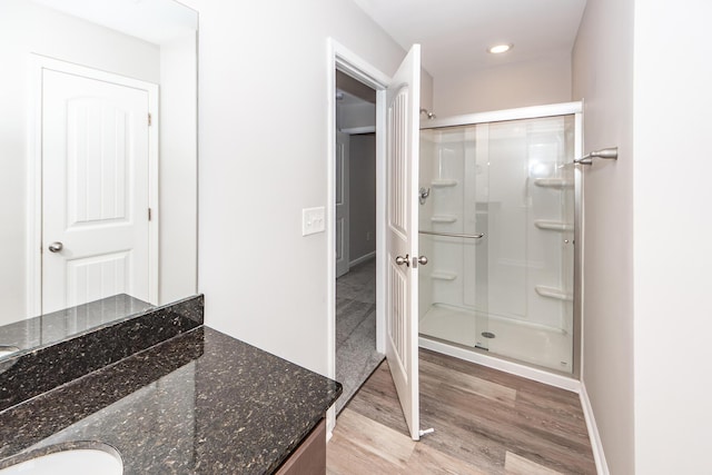 full bathroom featuring a shower stall, vanity, baseboards, and wood finished floors