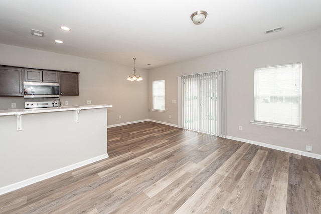 kitchen featuring stainless steel microwave, visible vents, a breakfast bar area, light countertops, and an inviting chandelier