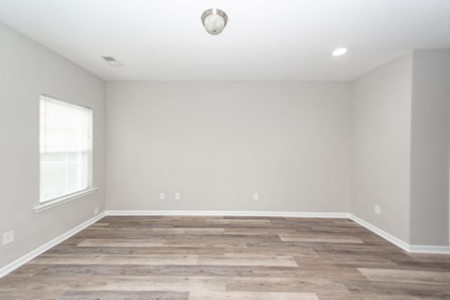 empty room with recessed lighting, visible vents, baseboards, and wood finished floors