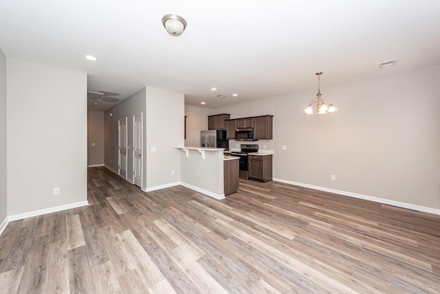 kitchen with stainless steel appliances, a peninsula, open floor plan, and light countertops