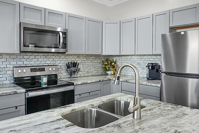 kitchen with tasteful backsplash, stainless steel appliances, gray cabinets, and sink