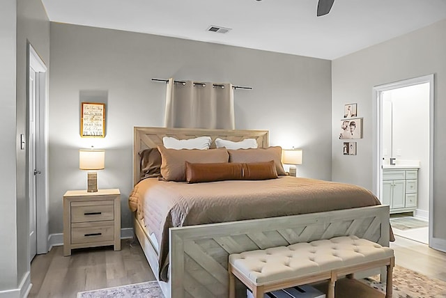 bedroom featuring ceiling fan, light wood-type flooring, and ensuite bath