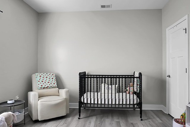 bedroom featuring a nursery area and light wood-type flooring