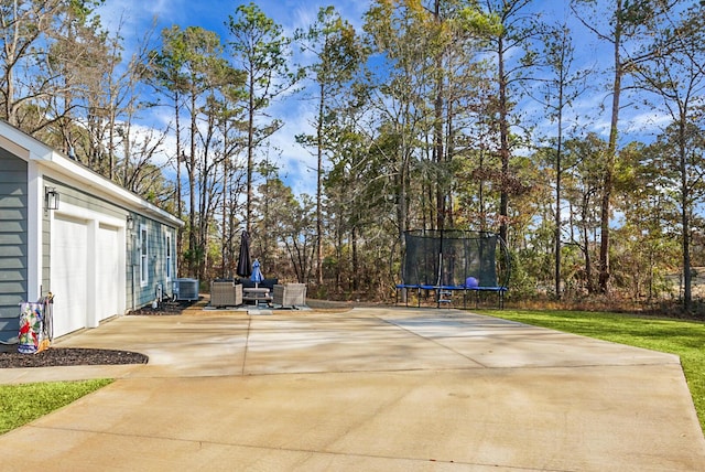 view of patio / terrace with a garage, central AC, and a trampoline