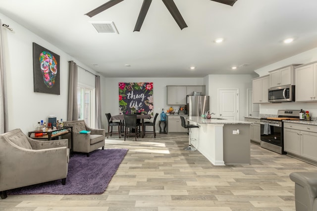 kitchen featuring gray cabinets, a kitchen island with sink, and stainless steel appliances