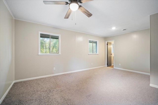 carpeted spare room with a wealth of natural light, ornamental molding, and ceiling fan