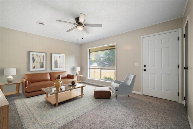 carpeted living room featuring ceiling fan, crown molding, and a textured ceiling