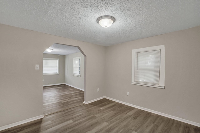 spare room with a textured ceiling and dark wood-type flooring