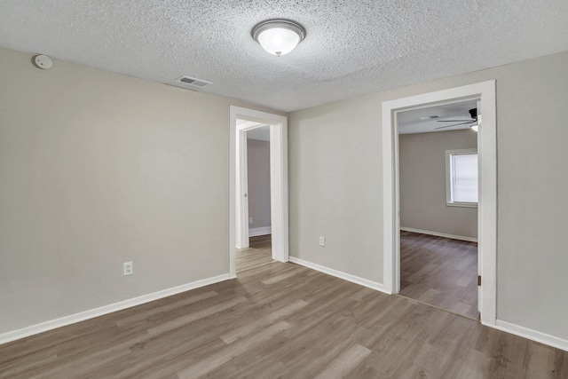 spare room with ceiling fan, a textured ceiling, and light wood-type flooring