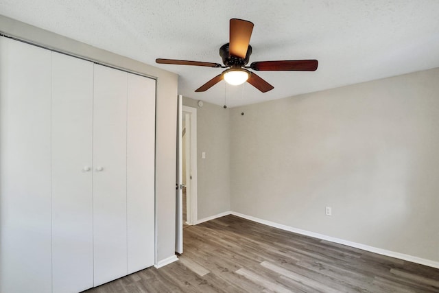 unfurnished bedroom featuring hardwood / wood-style flooring, ceiling fan, a textured ceiling, and a closet