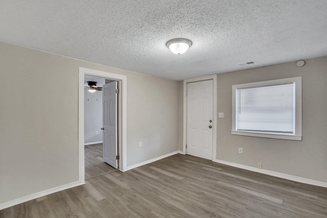 spare room featuring ceiling fan, wood-type flooring, and a textured ceiling