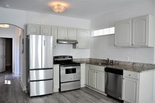 kitchen with white cabinets, stainless steel appliances, hardwood / wood-style flooring, and dark stone countertops