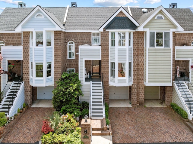 view of front of house featuring brick siding, decorative driveway, and stairs