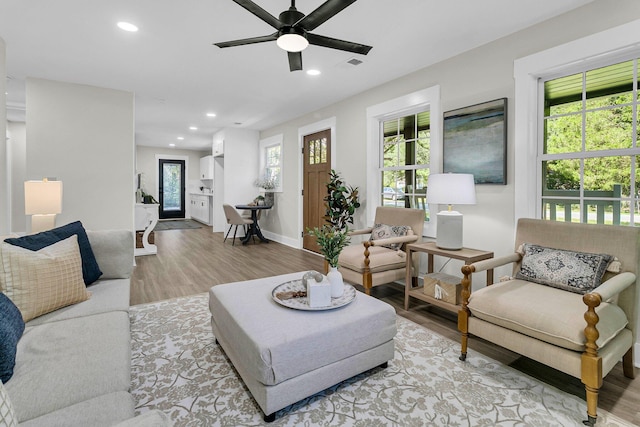 living room featuring light hardwood / wood-style flooring, ceiling fan, and a healthy amount of sunlight