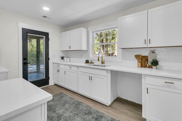 kitchen featuring white cabinets, plenty of natural light, light wood-type flooring, and sink